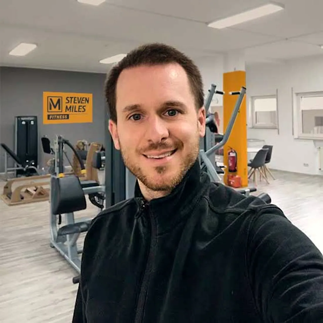Headcoach Stefan in seinem Studio, hinter ihm das Steven-Miles-Logo an der Wand